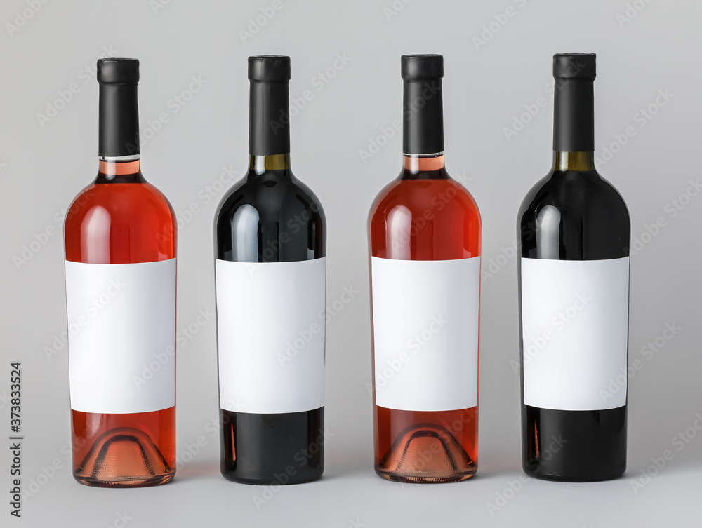 Bottles of wine with blank labels on light background. Mockup for design