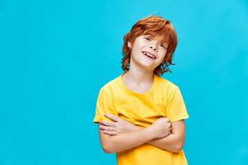 Wall Mural - child with red hair has his arms crossed over his chest and smiles against Copy Space