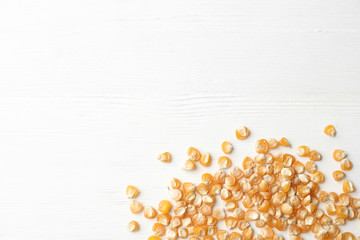 Raw dry corn seeds and space for text on white wooden background, flat lay. Vegetable planting