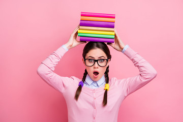 Wall Mural - Photo of pretty student lady hold literature pile on head preparing examination college university big homework overwhelmed wear shirt pullover specs isolated pink color background