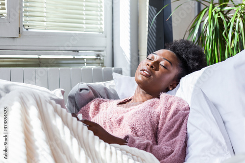 Fotografía Sick young african woman feeling cold covered with blanket sit on bed, ill black