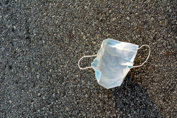 Health care and protection from COVID-19 concept, A piece of blue surgical mask thrown away on the street after use, Waste procedure or medical mask on street.