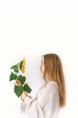 Beautiful young woman in linen dress holding sunflower on white background. Autumn concept.