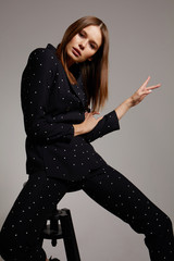 High fashion portrait of young elegant woman in black suit.