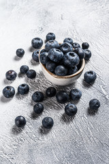 Wall Mural - Blueberries in a white ceramic bowl. Gray background. Top view