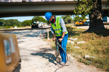 Wall Mural - Young male road construction worker on his job. Bright sunny day. Strong light.