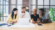© BullRun - Group of thoughtful multiethnic coworkers using laptop at office