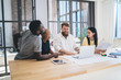 © BullRun - Group of confident multiethnic coworkers using laptop in office
