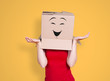 Person with cardboard box on its head and a smiling face stretching its hands out inquiringly on orange background