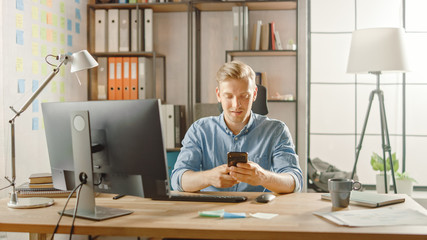 Aufkleber - Creative Entrepreneur Sitting at His Desk Works on Desktop Computer in the Stylish Office, Picks up and Starts Using Smartphone, Uses Social Media App, Emailing Business Partners, Messaging Friends