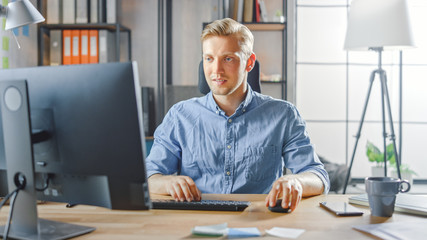 Poster - Creative Entrepreneur Sitting at His Desk Works on Desktop Computer in the Stylish Office. Handsome Young Businessman Uses Computer, Does Outsourcing Job, Designs New Apps and Develops Software