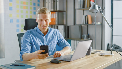 Poster - Creative Entrepreneur Sitting at His Desk Works on Desktop Computer in the Stylish Office, Picks up and Starts Using Smartphone, Uses Social Media App, Emailing Business Partners, Messaging Friends