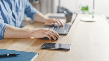 Poster - Close-up Shot of a Businessman Sitting at His Desk Works on Desktop Computer in the Stylish Office. His Smartphone Lies Near Him.