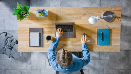Aufkleber - Top View Shot: Businessman Sitting at the Wooden Desk Works on a Laptop in his Home Office. He Types, Writes Emails, Surfs the Internet, Designs Software, Online Shopping
