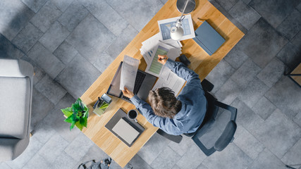 Poster - Businessman Sitting at His Desk in the Office Uses Laptop Computer, Working with Company Strategy Documents, Correcting Charts, Drawing Graphs and Statistics. Top View Shot
