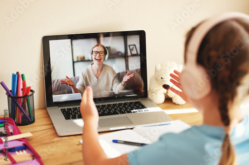 Cuadros en Lienzo schoolgirl wearing headphones communicates via video link with an online teacher