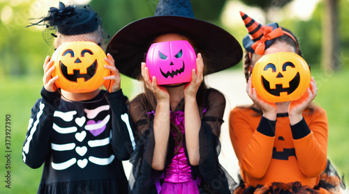 Fotografía Happy Halloween! funny children in carnival costumes hide their heads behind buckets pumpkins outdoors