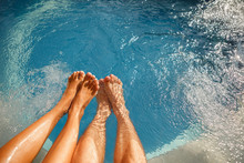 Happy Romantic Couple Enjoying A Bath In Jacuzzi. Male And Female Legs In The Swimming Pool. Young Relaxed Couple In Spa
