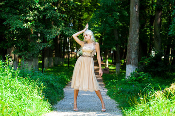 Young beautiful blonde girl in beige dress, summer park outdoor