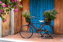 Vintage Bike With Basket Full Of Flowers Next To An Old Building In Danang, Vietnam, Close Up