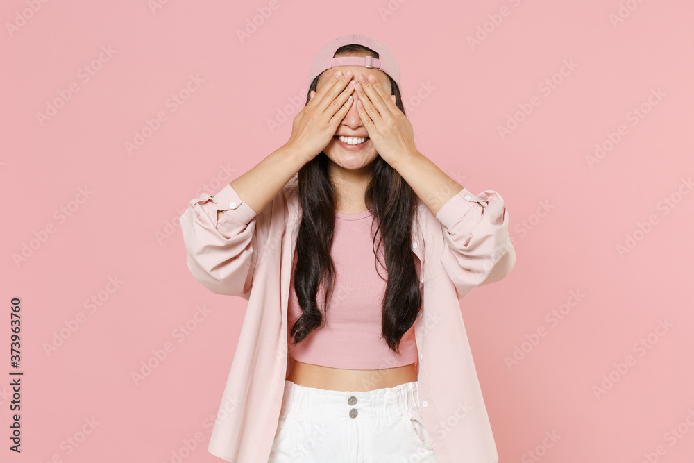 Smiling young asian woman girl in casual clothes cap posing isolated on pastel pink background studio portrait. People emotions lifestyle concept. Mock up copy space. Hiding, covering eyes with hands. - obrazy, fototapety, plakaty 