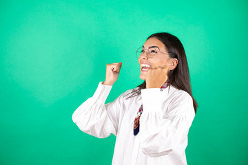 Young beautiful business woman over isolated green background smiling with her fists in the air with a gesture of victory