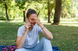 Young sad woman sitting in the park holding mobile phone and crying she got the bad news