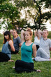 © Andrii - A group of people do yoga in the Park at sunset. Healthy lifestyle, meditation and Wellness