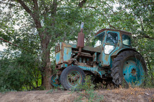 Vintage Photo - An Old Blue Tractor Standing Under A Green Branching Tree