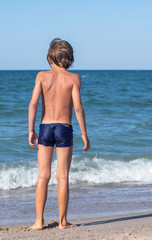 happy boy walks into the sea, vertical format