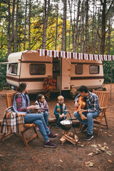 happy family on a camping trip relaxing in the autumn forest. camper trailer. fall season outdoors t