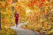 © Maridav - Autumn forest run path. Fall trail runner woman running in beautiful foliage woods nature background. Asian happy sports woman training outdoor. Active lifestyle girl jogging exercise.