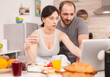 © DC Studio - Young couple using laptop at the kitchen. Happy married husband and wife in pajamas using internet web online modern technology, smiling and happy in the morning. Reading news browsing internet