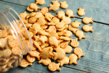 Overturned Jar With Goldfish Crackers On Blue Wooden Table, Closeup