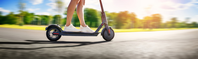 Woman riding on scooter in park in summer