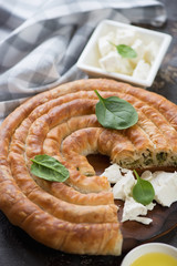 Wall Mural - Closeup of sliced spanakopita or Greek spiral spinach and feta cheese pie, vertical shot, selective focus