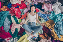 High Angle Above View Photo Of Pretty Focused Lady Stay Home Quarantine Spring Cleaning Household Lying Many Clothes Heap Stack Floor Prepared Untidy Dirty Stuff Resting Meditating Indoors
