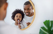 © paulaphoto - Portrait of happy family black African American father and son child boy brushing teeth in the bathroom. Morning routine with toothbrushes, father’s day concept