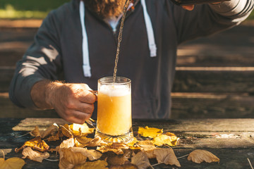 Cropped image of young man pouring fresh beer into pint glass, autumn holidays celebration and Oktoberfest concept