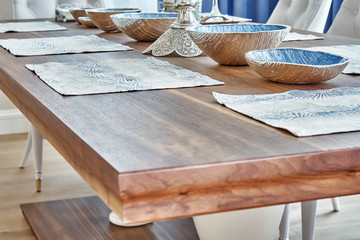 Wall Mural - Wooden dinner table with dishware. Blurred foreground