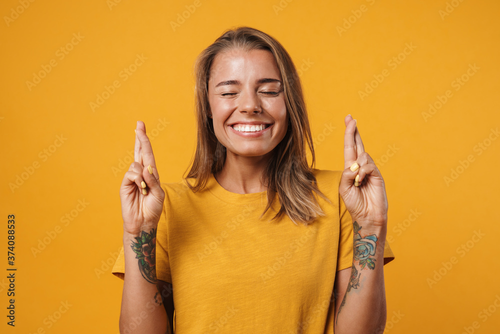 Image of blonde excited woman holding fingers crossed for good luck - obrazy, fototapety, plakaty 