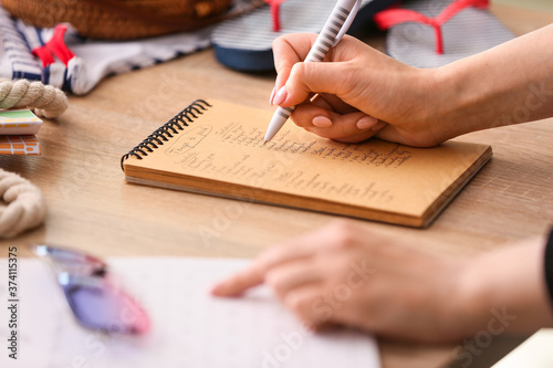 Fotomural Woman making check-list of things to pack for travel