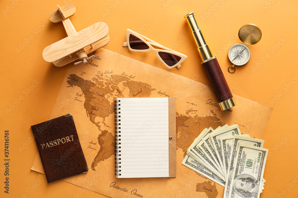 Notebook with travel accessories and world map on color background