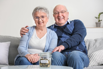 Poster - Senior couple with savings in jar at home