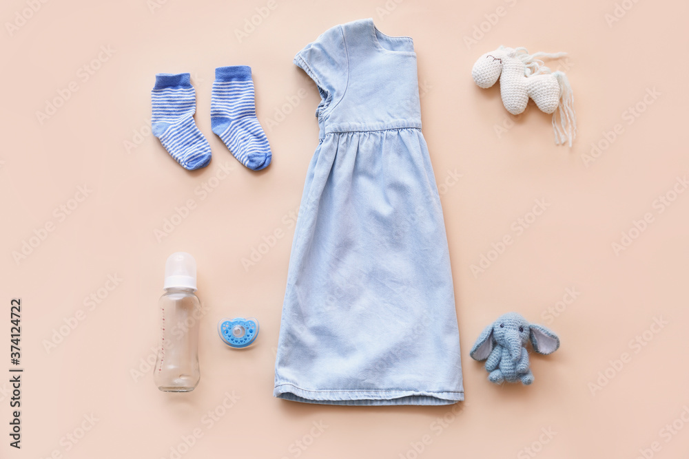 Baby clothes with bottle, pacifier and toys on color background