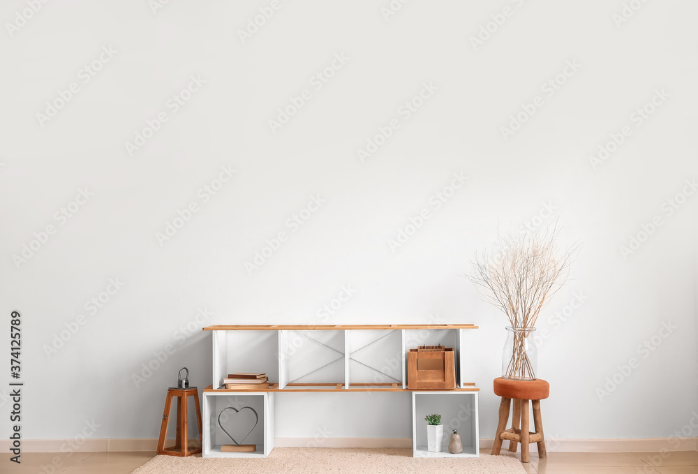 Stylish stand with decor near light wall in room
