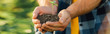 © LIGHTFIELD STUDIOS - cropped view of farmer holding ground with young plant in cupped hands, website header