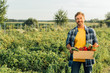 © LIGHTFIELD STUDIOS - rancher in plaid shirt holding box with fresh vegetables while standing on plantation