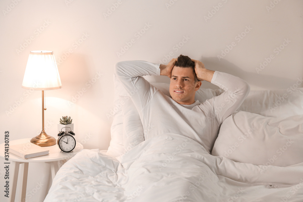 Young man suffering from insomnia in bedroom