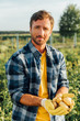 © LIGHTFIELD STUDIOS - farmer in checkered shirt holding fresh, organic potatoes in cupped hands while looking at camera